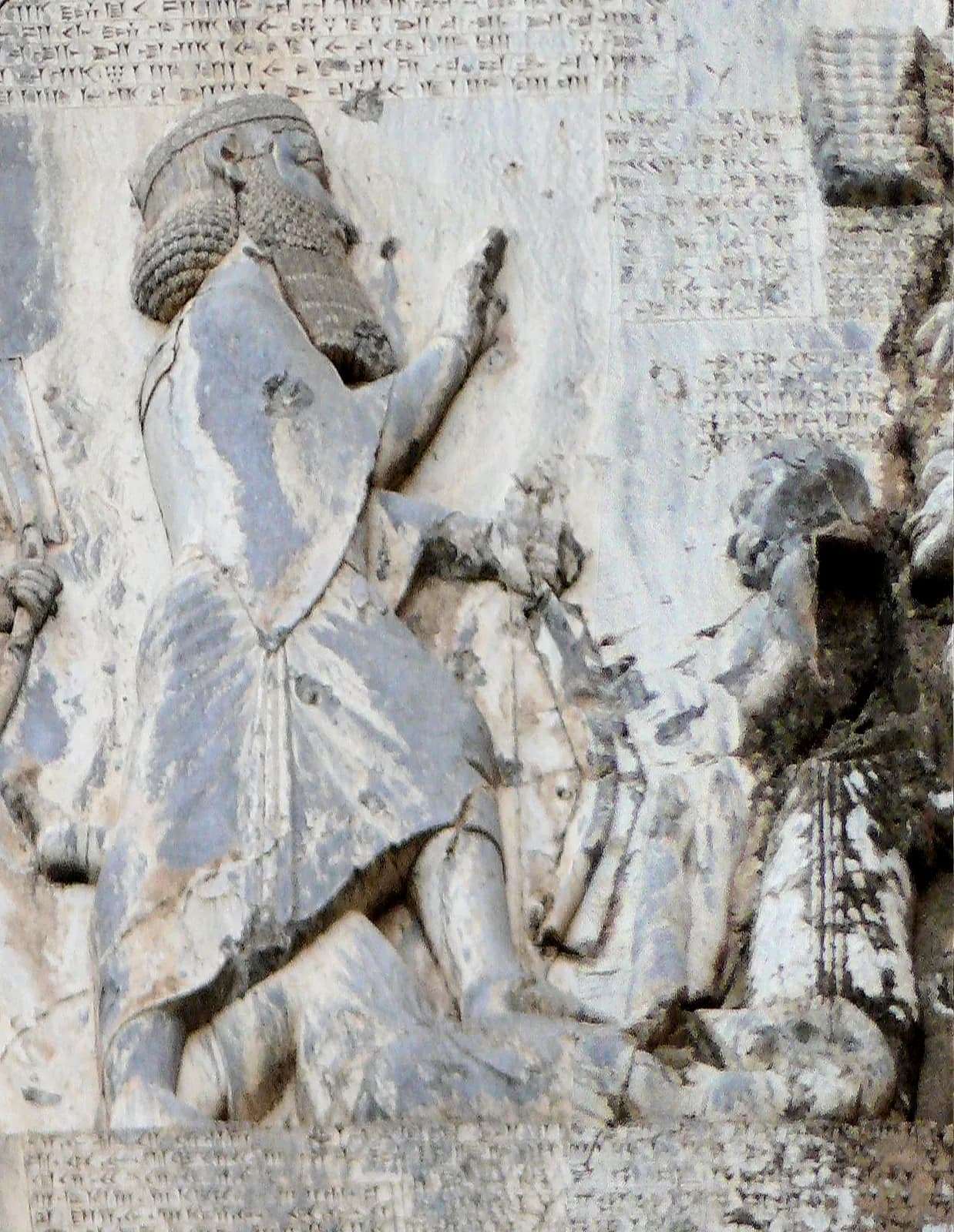 The relief of the Behistun Inscription — Darius I, bow in hand, treading on the prostrate usurper Gaumata, facing a line of bound rebel kings, beneath the winged symbol of Ahuramazda.