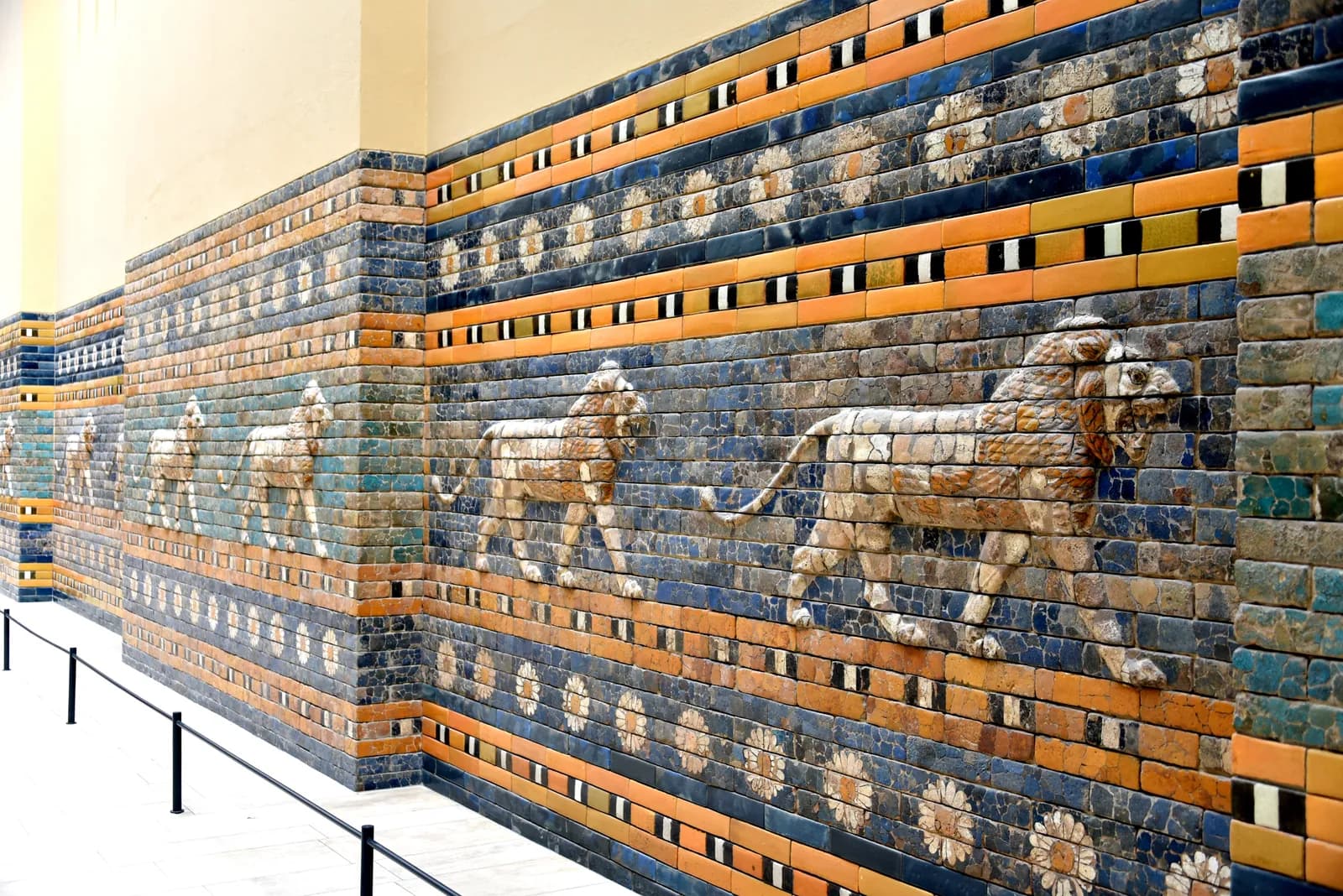 Reconstructed wall of the Processional Way of Babylon, ranked with striding lions in moulded relief on a field of lapis-blue glazed brick — the lion of Ishtar, emblem of the city.