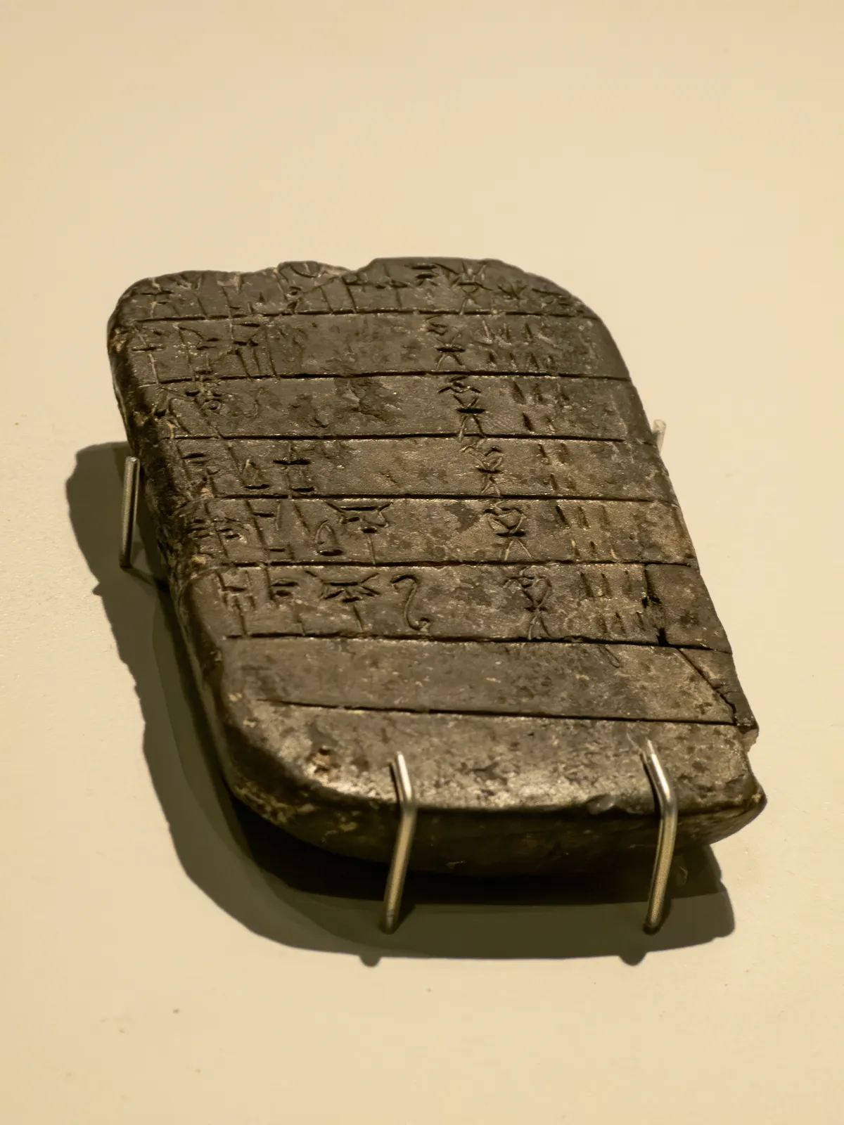 Small rectangular clay tablet incised with horizontal lines of Linear B syllabic signs.