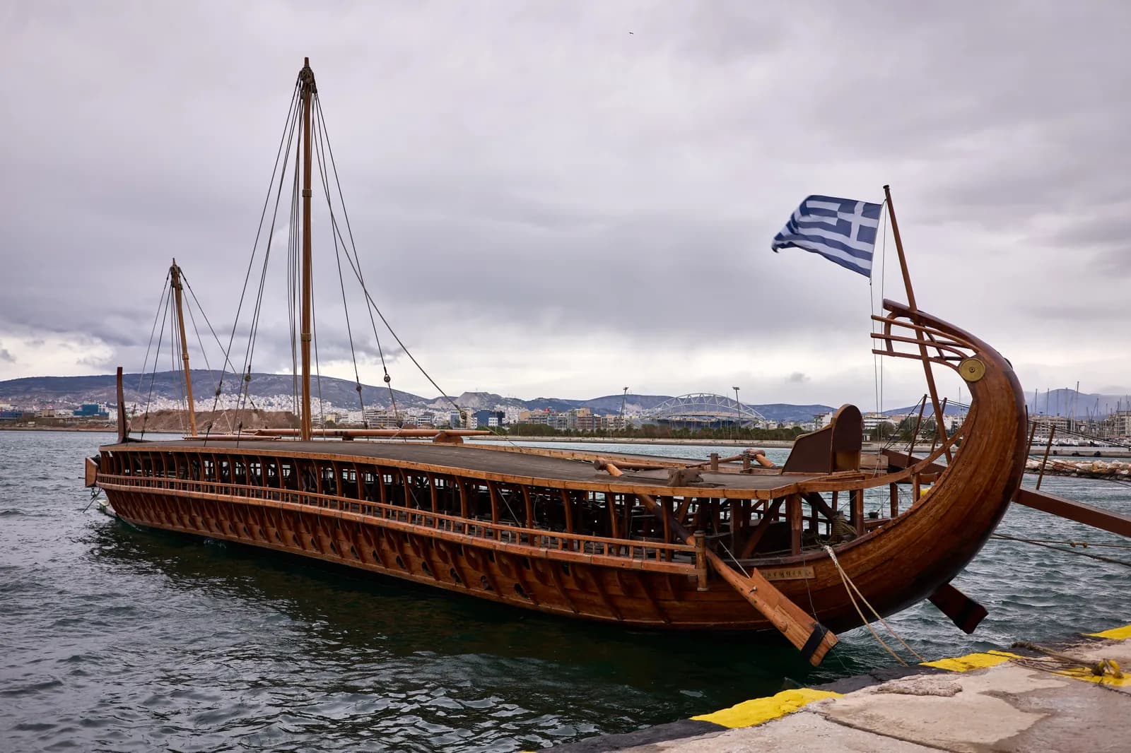 The Olympias, a modern full-scale reconstruction of an ancient Athenian trireme, its three banks of oars and bronze ram visible, afloat at Athens.