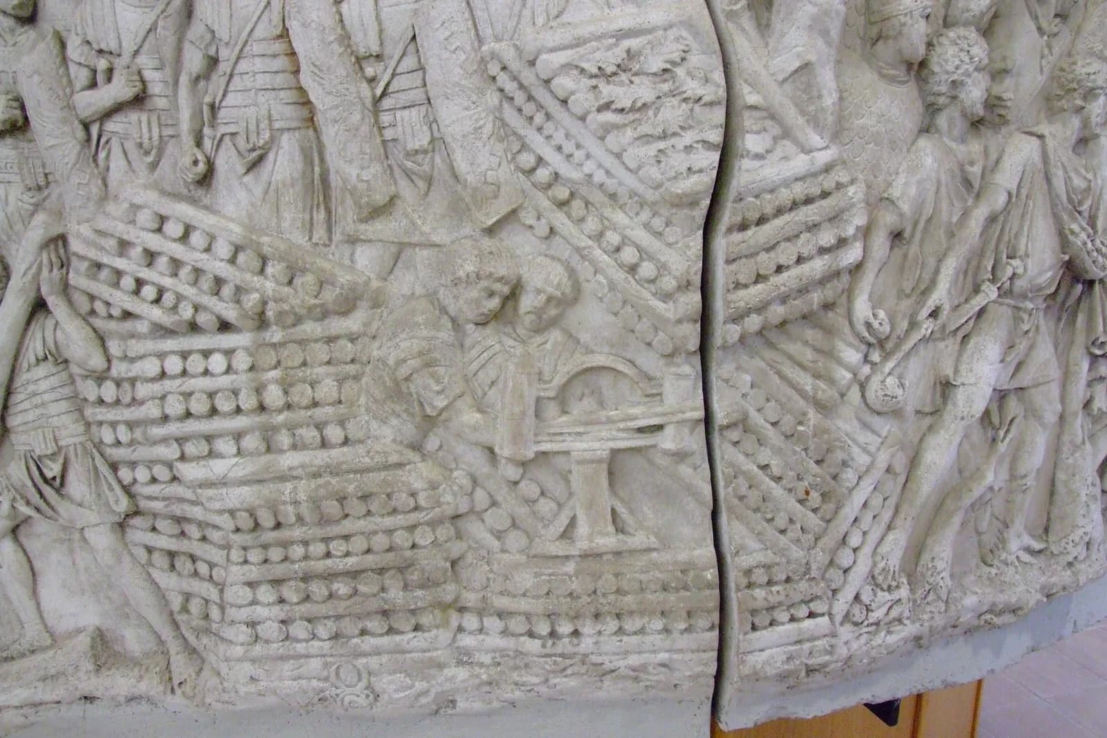 Carved relief showing a wheeled torsion engine with two arms and a slider, crewed by soldiers.