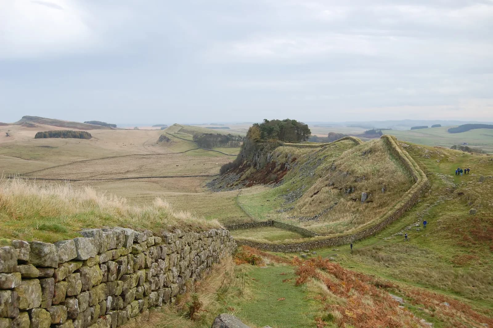 Stone wall running along the crest of a ridge across open moorland under a wide sky.