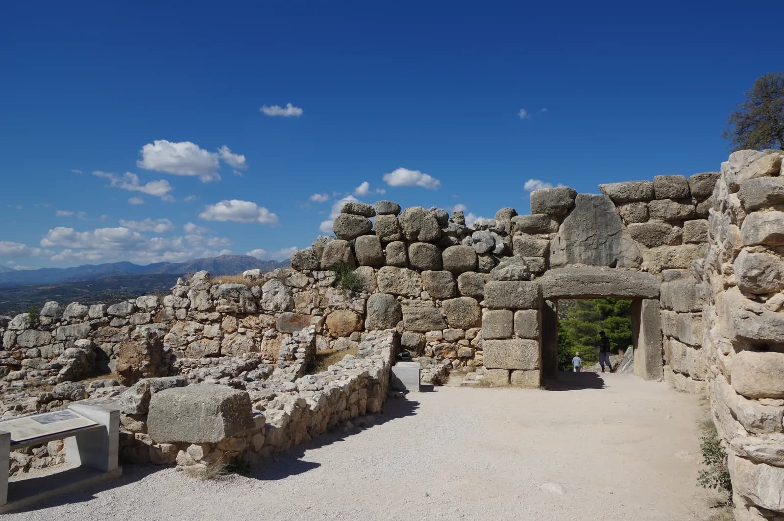 Hillside archaeological site of massive stone foundations and circuit walls under open sky.