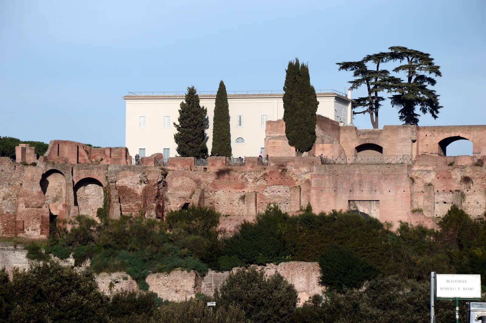 Brick and concrete walls of a many-roomed palace on several levels, arranged around sunken courtyards, on a hilltop above the city.