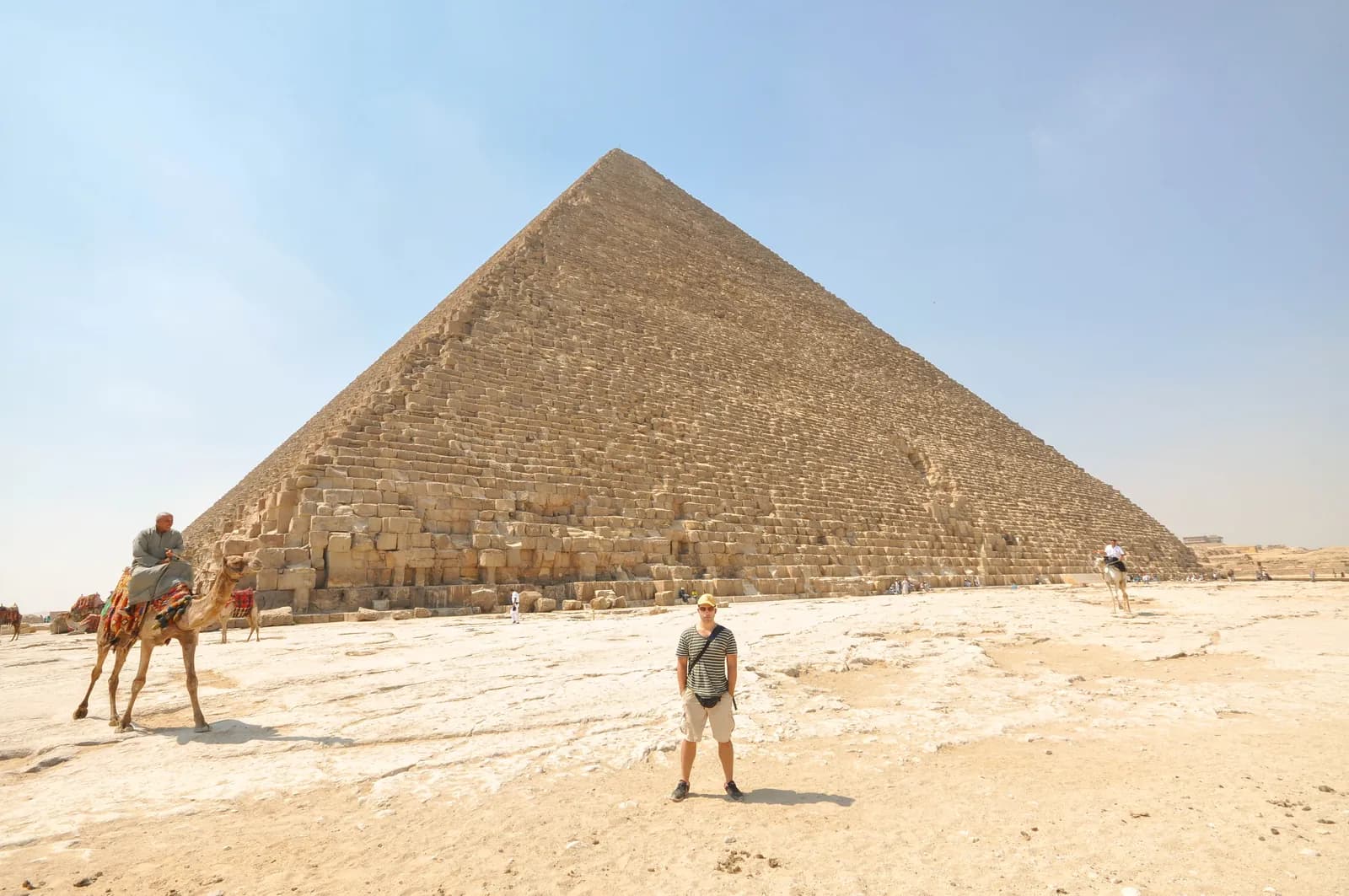 A vast stepped pyramid of weathered limestone blocks rising against the sky, its surface rough where the smooth casing has been removed.