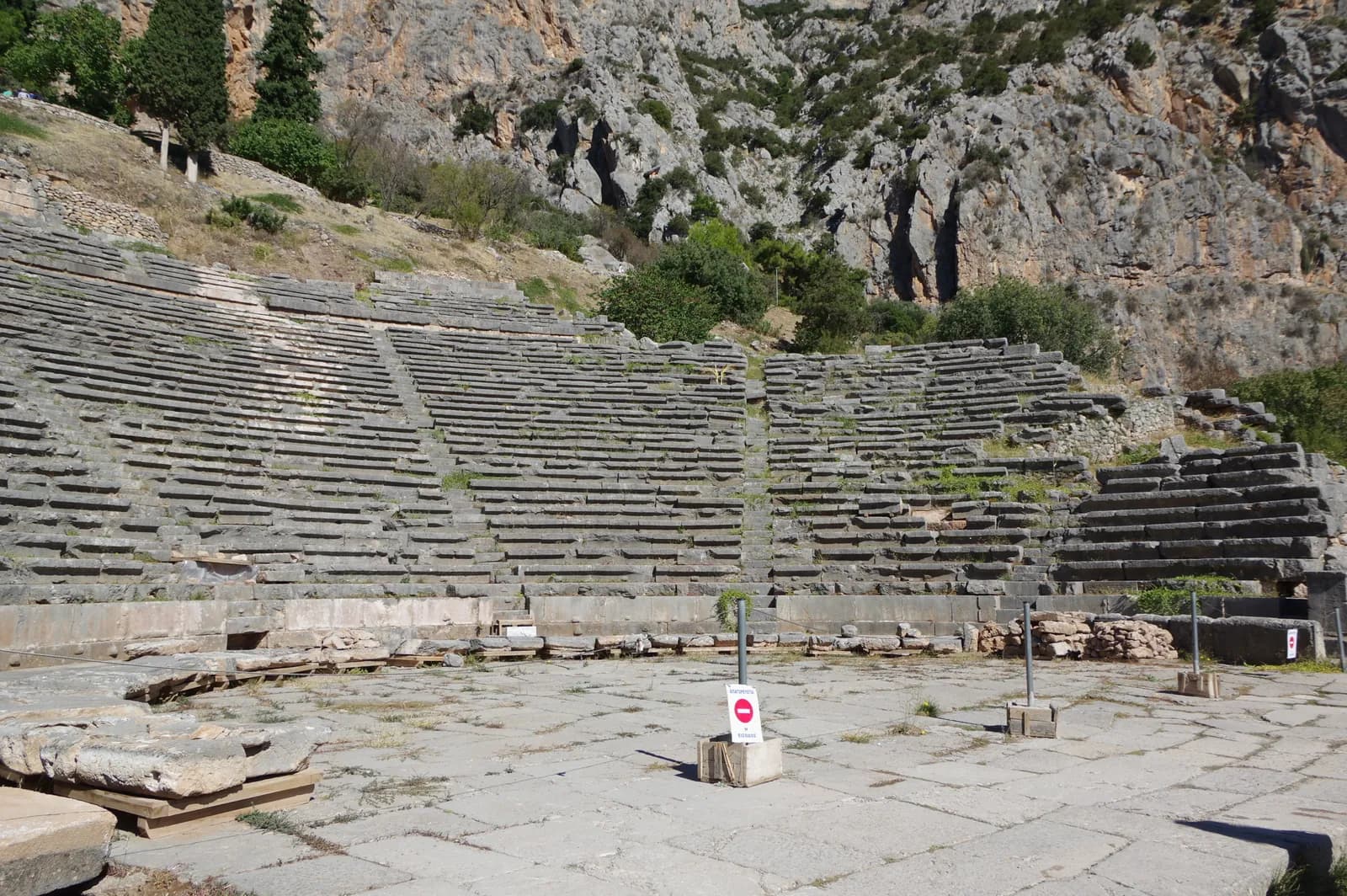 The archaeological site of the sanctuary of Apollo at Delphi stepping up the slope of Mount Parnassus, the foundations and standing columns of the temple terrace among the rocks.