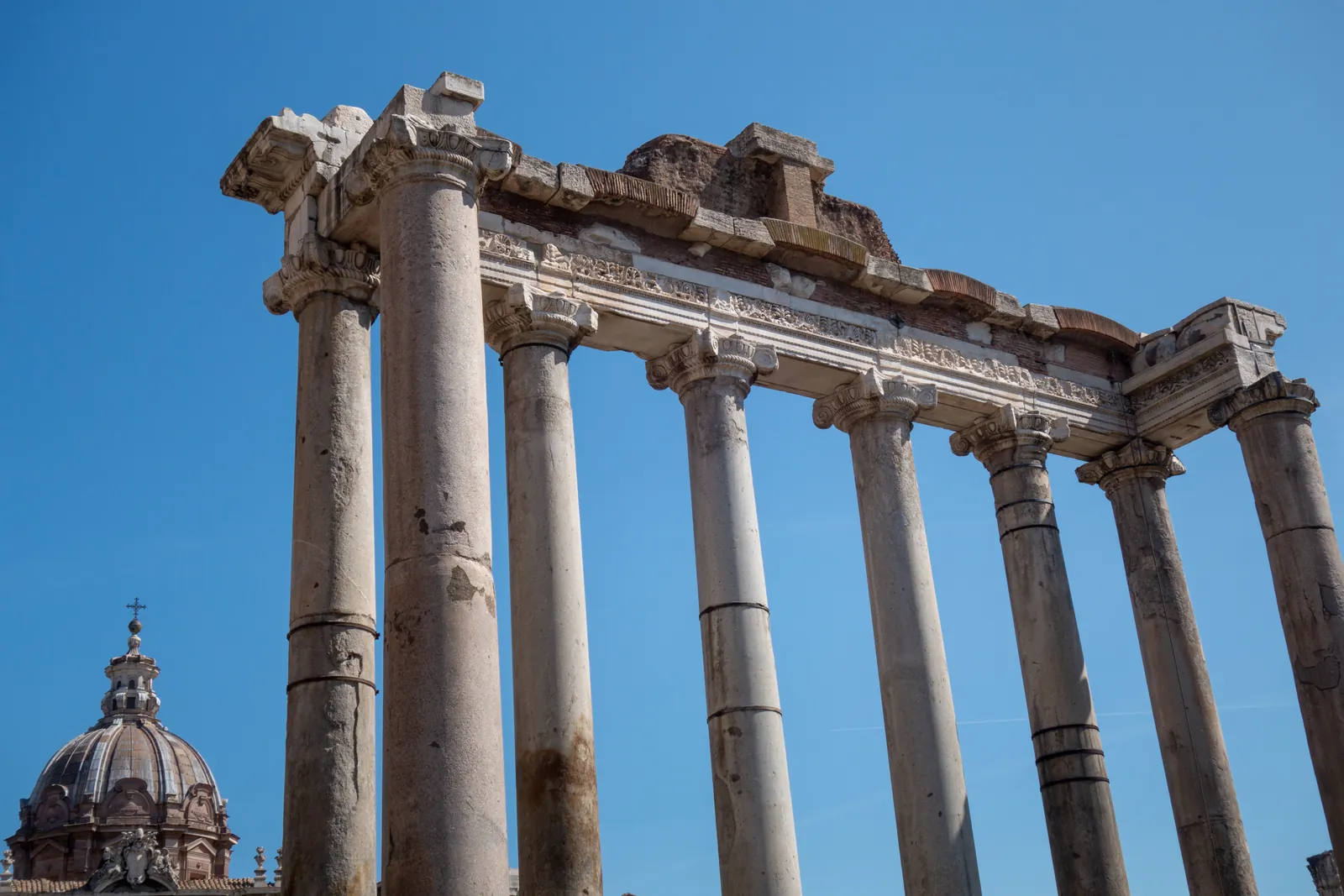 Eight granite columns of differing colours carrying a fragment of inscribed marble entablature, on a high stone podium.